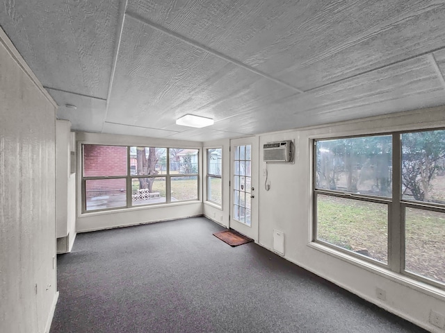 carpeted empty room with a wall unit AC and a textured ceiling