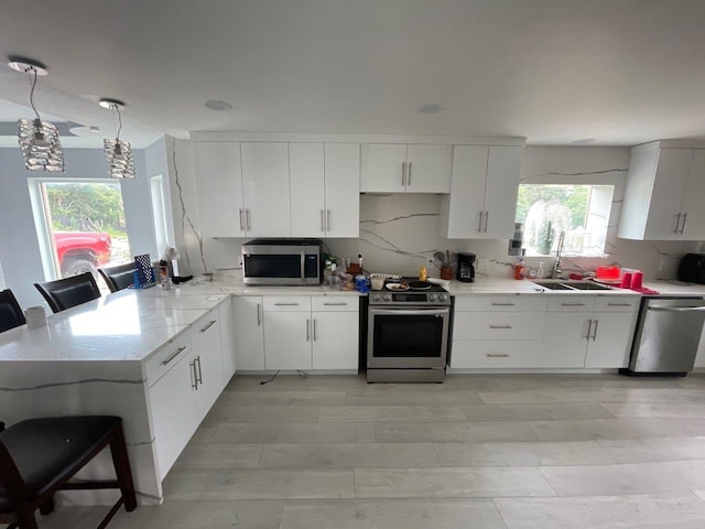 kitchen with white cabinetry, appliances with stainless steel finishes, a kitchen breakfast bar, and sink