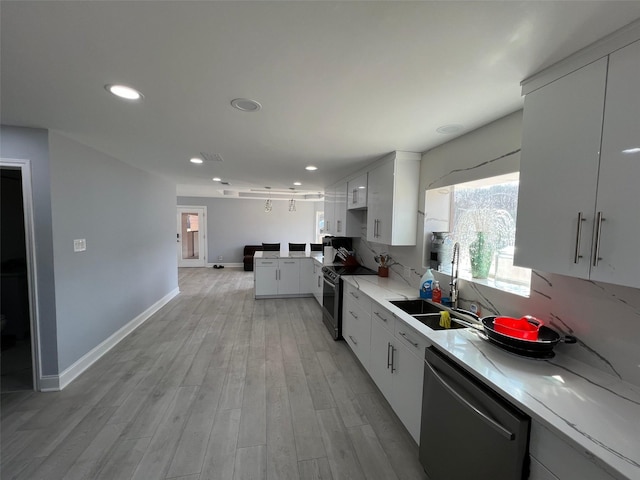 kitchen featuring sink, light hardwood / wood-style flooring, appliances with stainless steel finishes, white cabinets, and decorative backsplash