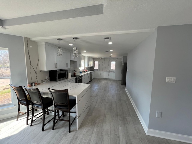 kitchen with light hardwood / wood-style flooring, kitchen peninsula, a healthy amount of sunlight, and appliances with stainless steel finishes