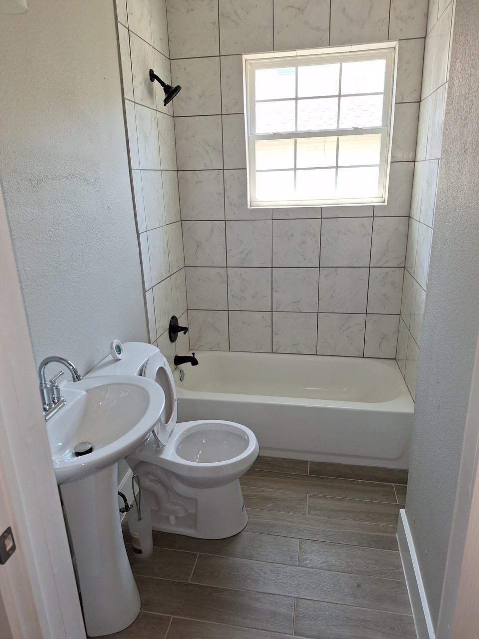 bathroom with tiled shower / bath combo and toilet