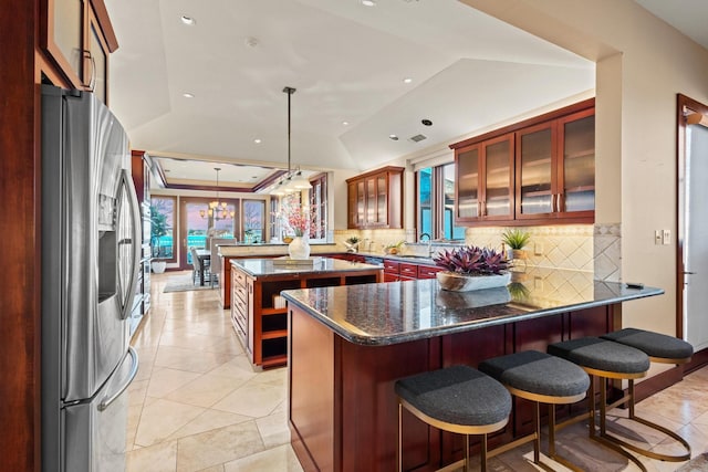 kitchen with a breakfast bar, a center island, stainless steel fridge with ice dispenser, decorative light fixtures, and kitchen peninsula