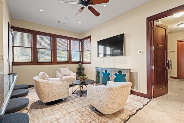 living room featuring ceiling fan, washer / dryer, and a wealth of natural light