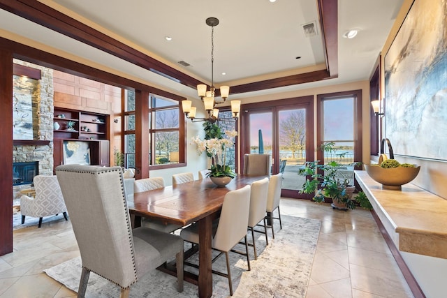 tiled dining room featuring a notable chandelier, a fireplace, and a tray ceiling