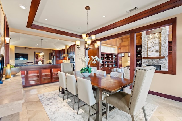 dining area with a tray ceiling, a fireplace, and a chandelier