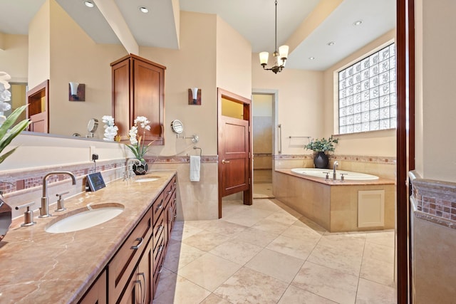 bathroom with tile walls, vanity, a relaxing tiled tub, a notable chandelier, and tile patterned floors