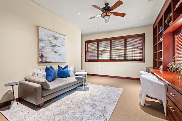 carpeted living room with built in desk and ceiling fan