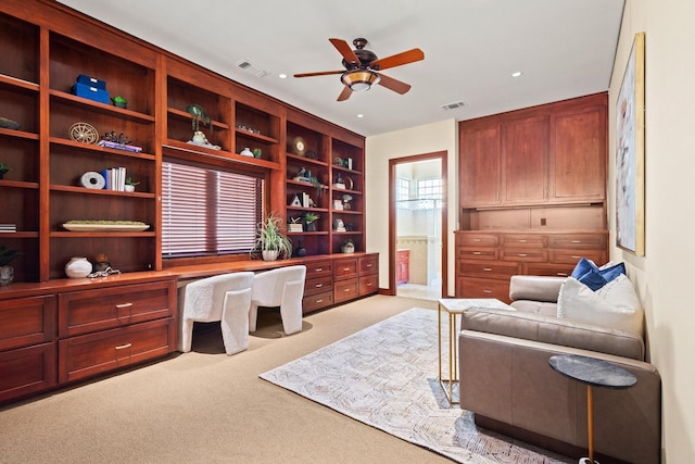 office space featuring light carpet, built in desk, and ceiling fan