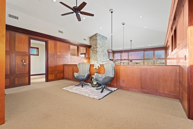 sitting room with ceiling fan, high vaulted ceiling, light carpet, and wood walls