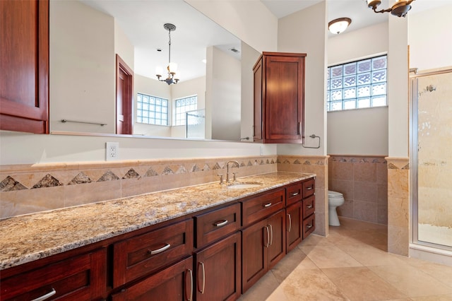 bathroom with tile walls, tile patterned flooring, vanity, toilet, and a chandelier