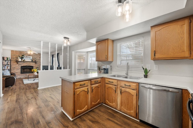 kitchen featuring sink, dishwasher, dark hardwood / wood-style floors, a brick fireplace, and kitchen peninsula