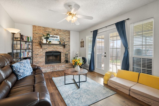 living room featuring dark hardwood / wood-style floors, a fireplace, ceiling fan, a textured ceiling, and french doors