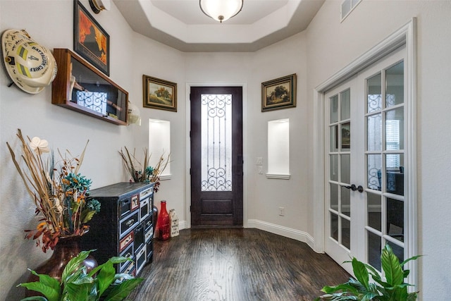 foyer entrance with a raised ceiling, dark hardwood / wood-style floors, and french doors