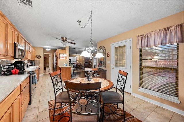 dining area featuring ceiling fan with notable chandelier, a textured ceiling, and light tile patterned flooring