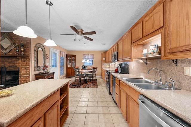 kitchen with sink, stainless steel appliances, tasteful backsplash, a fireplace, and decorative light fixtures