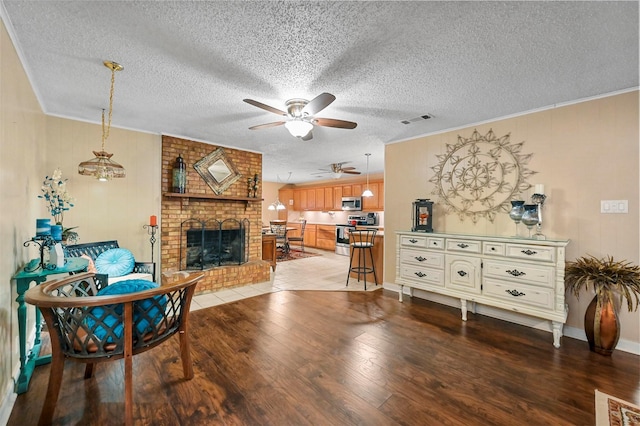 living room with wood-type flooring, crown molding, a textured ceiling, and a fireplace