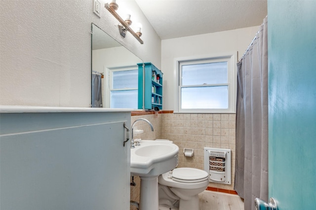 bathroom featuring tile walls, hardwood / wood-style flooring, heating unit, and toilet