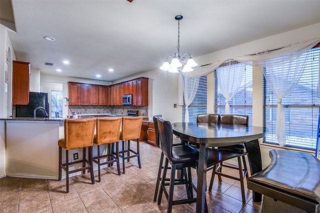 dining room featuring plenty of natural light, light tile patterned floors, and an inviting chandelier