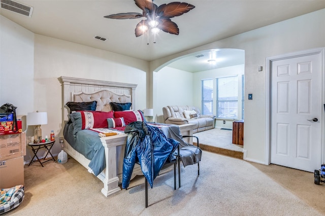 bedroom featuring arched walkways, ceiling fan, carpet flooring, and visible vents
