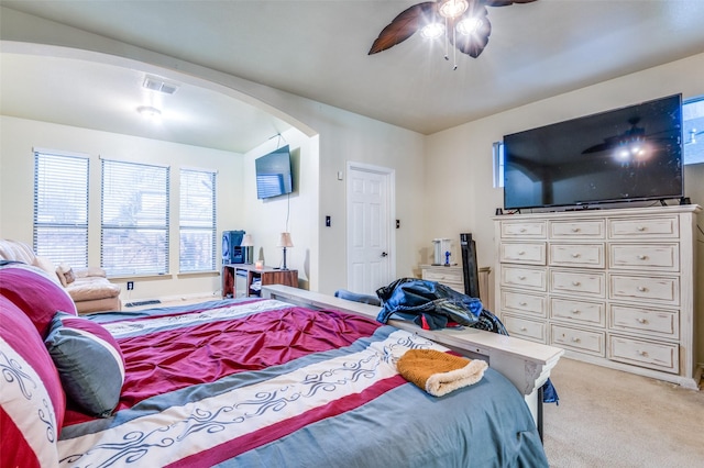 bedroom with light carpet, ceiling fan, visible vents, and arched walkways
