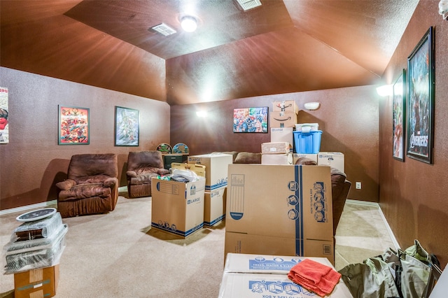 carpeted home theater featuring visible vents, a textured wall, and vaulted ceiling
