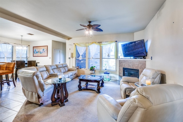 living room with ceiling fan, a tile fireplace, and light tile patterned floors