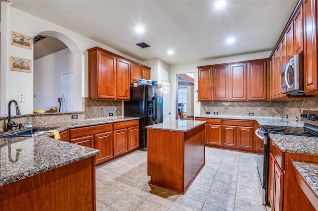 kitchen featuring arched walkways, a sink, recessed lighting, stainless steel appliances, and backsplash