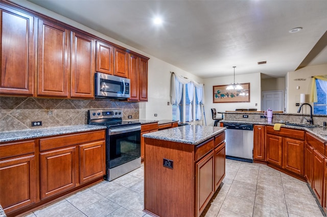 kitchen with stainless steel appliances, a kitchen island, sink, and light stone counters