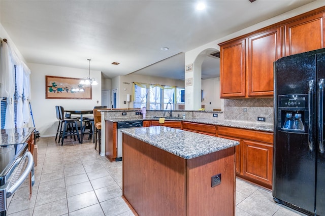 kitchen with a center island, appliances with stainless steel finishes, light tile patterned flooring, a sink, and brown cabinets