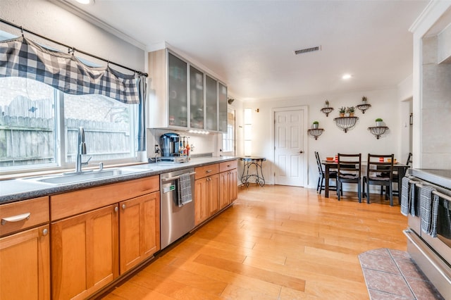 kitchen featuring sink, ornamental molding, stainless steel appliances, and light wood-type flooring