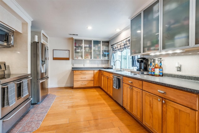 kitchen featuring sink, crown molding, stainless steel appliances, and light hardwood / wood-style floors