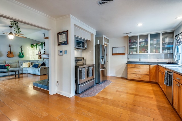 kitchen with sink, crown molding, light wood-type flooring, appliances with stainless steel finishes, and ceiling fan