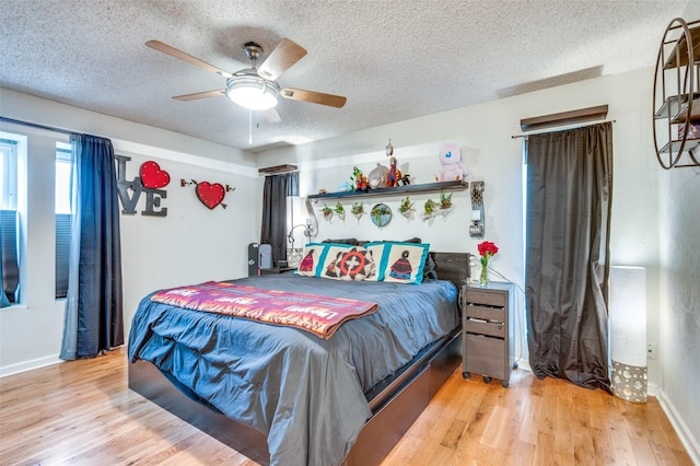 bedroom with ceiling fan, light hardwood / wood-style flooring, and a textured ceiling