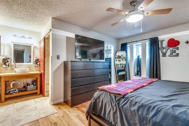 bedroom with sink, hardwood / wood-style flooring, a textured ceiling, and ceiling fan