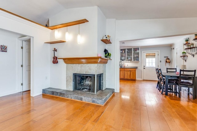 living area featuring light wood-type flooring, vaulted ceiling, and a fireplace