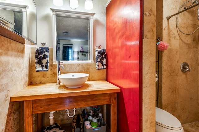 bathroom featuring a shower, vanity, a textured ceiling, and toilet