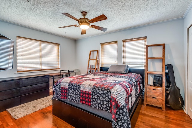 bedroom featuring crown molding, ceiling fan, hardwood / wood-style floors, and a textured ceiling