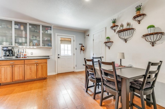 dining room with baseboards, ornamental molding, and light wood-style flooring