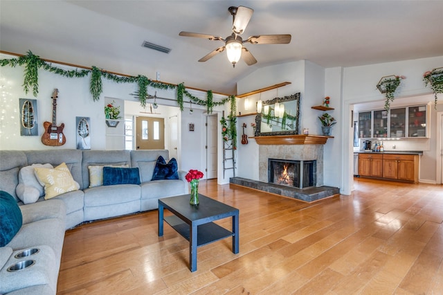 living room featuring a tiled fireplace, lofted ceiling, hardwood / wood-style floors, and ceiling fan