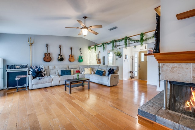 living room with lofted ceiling, hardwood / wood-style flooring, a premium fireplace, and ceiling fan