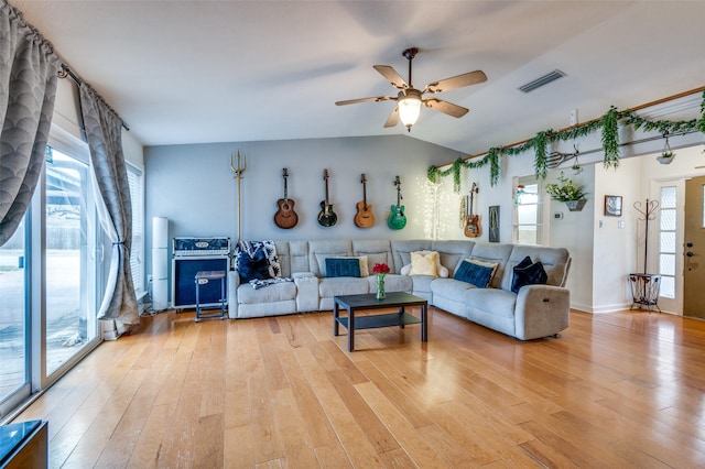 living room with a wealth of natural light, light hardwood / wood-style floors, and vaulted ceiling