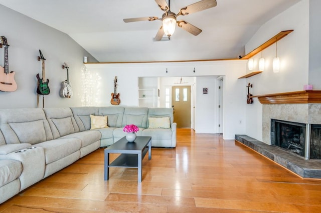 living area with lofted ceiling, a tile fireplace, wood finished floors, and ceiling fan