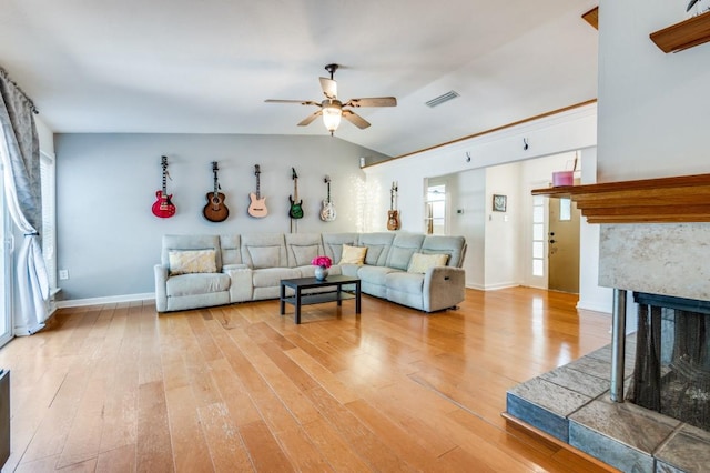 living area featuring a multi sided fireplace, visible vents, light wood-style floors, and ceiling fan