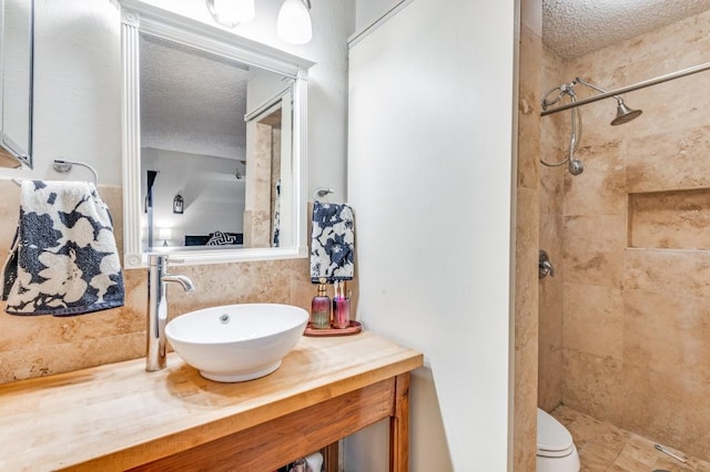 full bath featuring a tile shower, toilet, and a textured ceiling