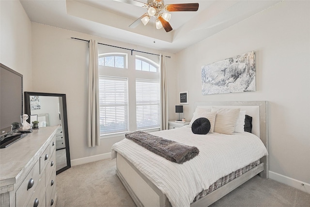 bedroom featuring light colored carpet, ceiling fan, and a tray ceiling