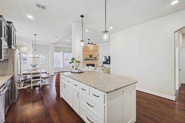 kitchen with ceiling fan with notable chandelier, pendant lighting, white cabinets, light stone counters, and dark wood-type flooring