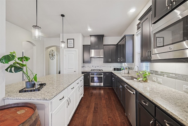 kitchen with appliances with stainless steel finishes, sink, white cabinets, a kitchen bar, and hanging light fixtures