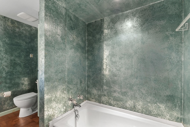 bathroom with a bathing tub, parquet floors, and toilet