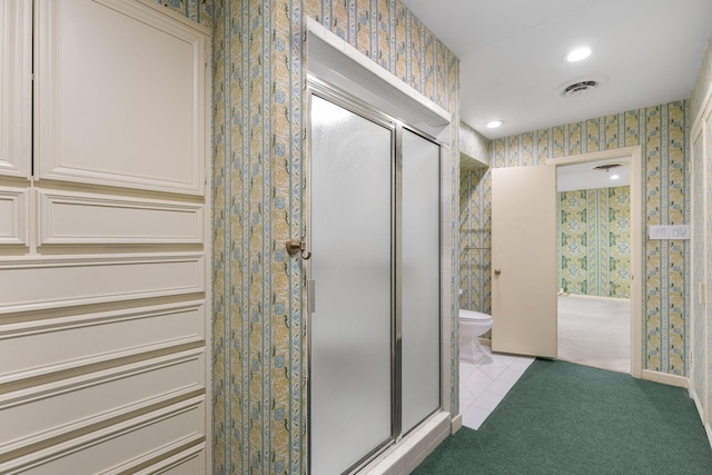 bathroom featuring walk in shower, toilet, and tile patterned flooring