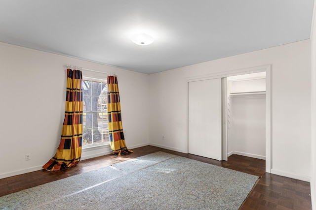 unfurnished bedroom with a closet and dark parquet floors